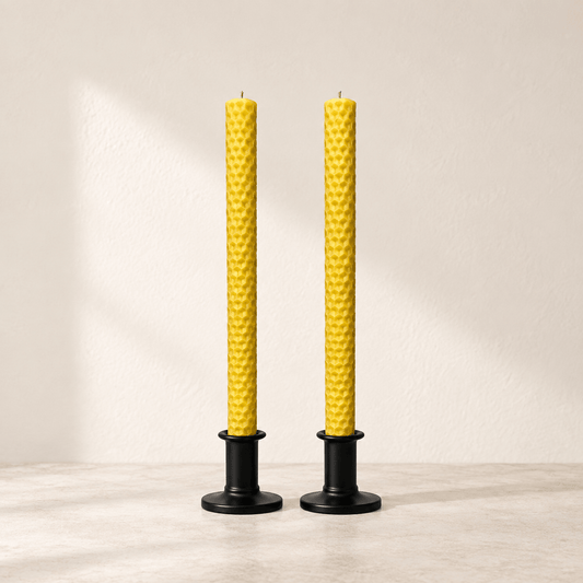Pair of golden honeycomb beeswax taper candles in black holders with breathing room around the full candles.